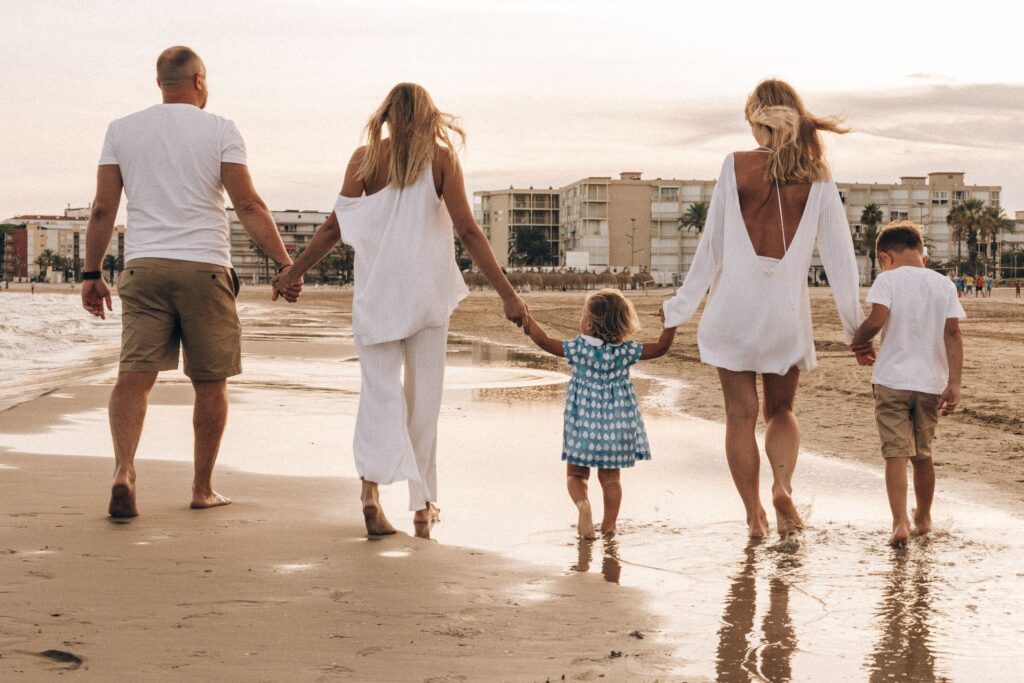 Familia paseando de la mano por la playa